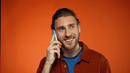 happy young man talking on mobile phone on orange