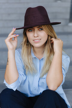 Young female in trendy hat relaxing in stairs