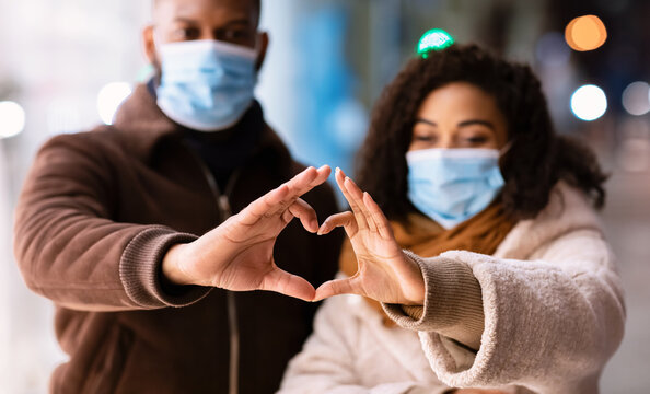 Black Couple In Masks Making Heart Shape With Hands