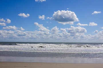 Obraz premium Beautiful white puffy cloudscape over a rough ocean with wild waves
