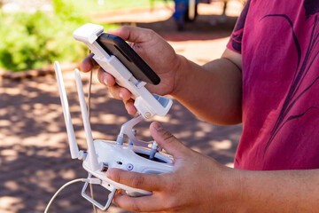 Close em m&atilde;os de rapaz usando um controle remoto para drone.