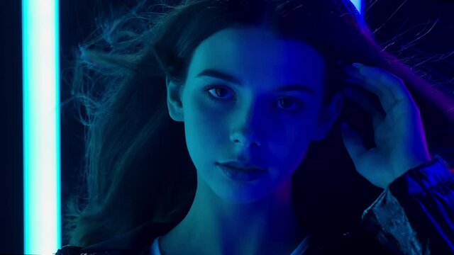 Portrait of a pretty young beautiful woman with hair flying in the wind looking at the camera. Close up. Slow motion.