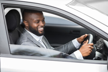 Happy black businessman driving home after working day