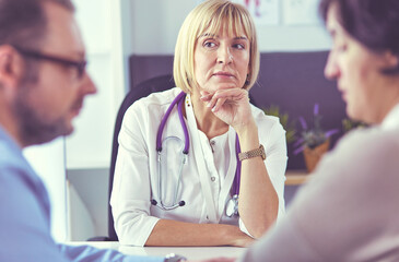 Attentive senior doctor listenint to patient in her office