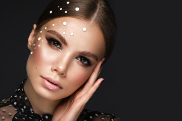Portrait of a beautiful woman in a black dress with pearls and classic makeup.