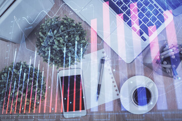 Multi exposure of financial chart hologram over desktop with phone. Top view. Mobile trade platform concept.