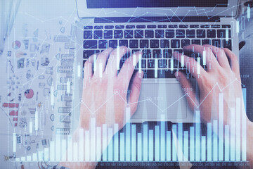 Double exposure of man's hands typing over laptop keyboard and forex chart hologram drawing. Top view. Financial markets concept.