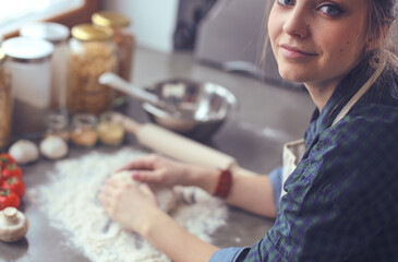 Young woman standing by the stove in the kitchen .