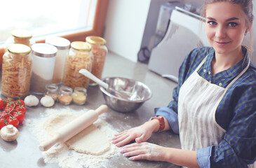 Beautiful woman cooking cake in kitchen standing near desk.