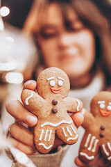 selective focus, noise effect: Merry Christmas and Happy New Year! Christmas cookies, gingerbread man figure holding a smiling woman in her hands