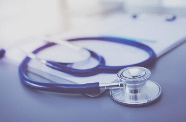 Stethoscope with black medical clipboard on wooden desk