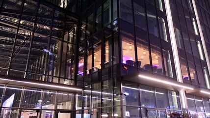 Pattern of office buildings windows illuminated at night. Lighting with Glass architecture facade design with reflection in urban city.