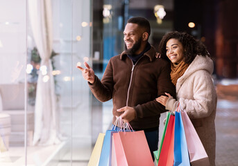 Portrait of happy black couple with shopping bags walking