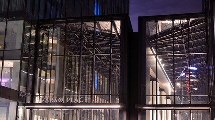 Fototapeta premium Pattern of office buildings windows illuminated at night. Lighting with Glass architecture facade design with reflection in urban city.