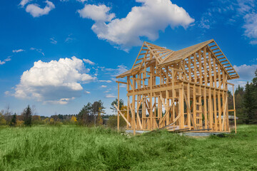 Frame of a cottage under construction against a beautiful sky. Construction of a private house in the countryside. Wooden country house under construction. Rural properties. New country houses. - obrazy, fototapety, plakaty