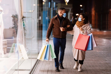 Portrait of happy black couple in masks with shopping bags