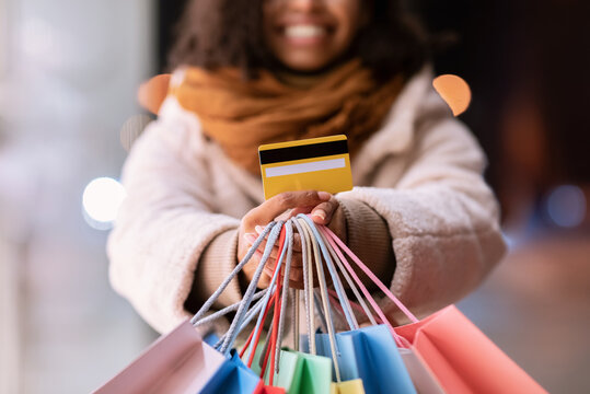 Unrecognizable black woman showing credit card and shopping bags