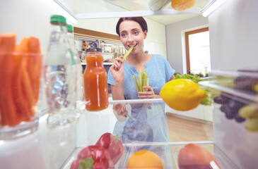 Young woman taking fresh healthy vegetables from the fridge and preparing lunch, diet and lifestyle concept
