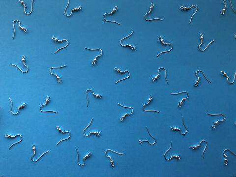 A pattern of earring hooks to create jewelry on a blue background. Basics for earrings, DIY jewelry.