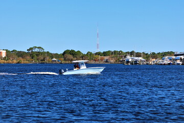 USA, Florida, Photo taken from Santa Rose Island - October 2020. Speedboat sails on the water of Santa Rosa Sound. The mainland coast is visible in the background