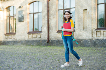 Make learning more enjoyable. Little child wear headphones outdoors. Modern technology in...