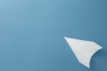 Fototapeta na wymiar White paper airplane on a blue background