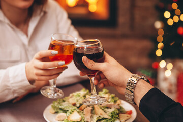 Man and woman drink red and white wine.  Сlose-up of hands with glasses. They celebrate the new year.