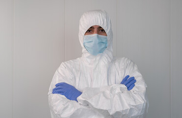 A health worker in a protective suit crosses his arms. Coronavirus pandemic.