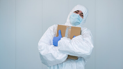 A happy health worker on protective suit hug a box of medical supplies. Covid 19