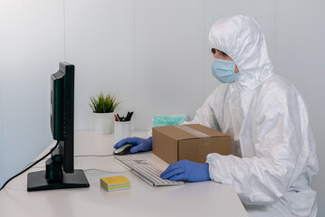 A nurse wears PPE and face mask, using the computer to send an order of new mask