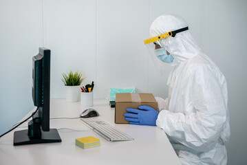 Doctor in protective suit packet a new medical masks in a box during Covid 19