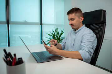 Portrait young businessman sitting and pointing finger at smartphone in office