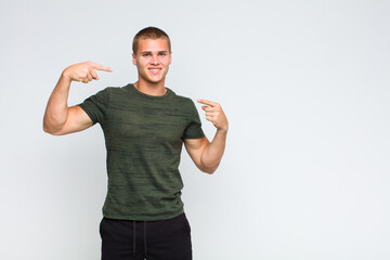 blonde  man smiling confidently pointing to own broad smile, positive, relaxed, satisfied attitude
