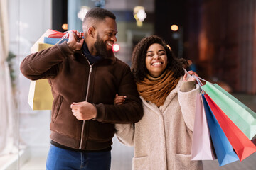 Portrait of happy afro couple walking with shopping bags