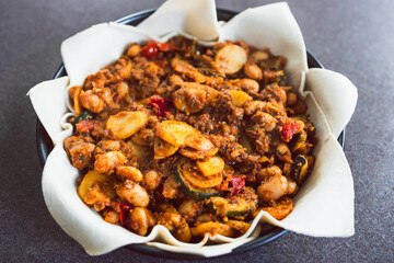 plant-based food, vegan pie with mediterranean vegetables potato and olive red pesto before going in the oven