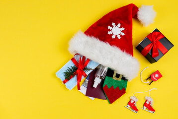 Santa hat, mask, disinfectant, passport, gift and christmas decor on the right on a yellow background with space for text on the left, top view close-up.