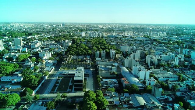 Video a&eacute;reo de una zona con parques p&uacute;blicos con &aacute;rboles antiguos y en el fondo, vemos la ciudad; durante el atardecer, en verano..