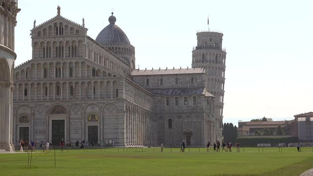Tourists Walking Around the Pisa Cathedral and Leaning Tower of Pisa.Basilica temple white monument statue sculpture asymmetric historic Europe high arches blind arche lozenge grey cornices cornice 4K