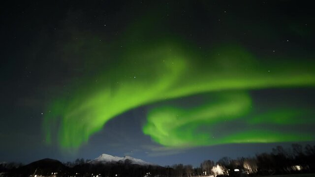 Northern Lights Taking Up Whole Sky with Lit Cabins Down Below and Mountains