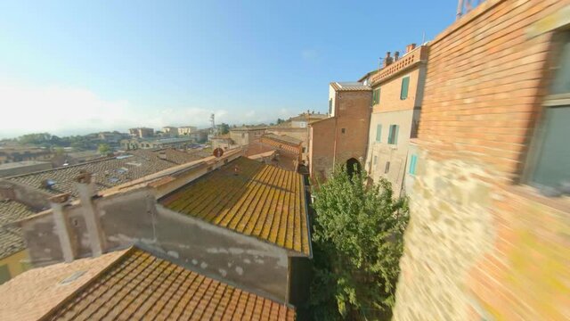 Close flight between the roofs of the medieval village Sinalunga in Tuscany, Italy. From the ground to the sky