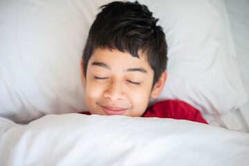 Teen boy sleeping in the bed with blanket cover happy smile face