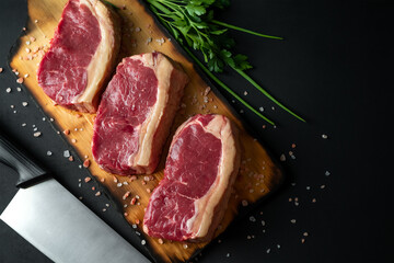 Three raw steaks on a cutting board