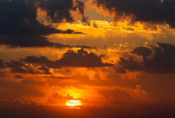 Fototapeta premium Multiple layers of clouds during sunset time. Dramatic cloudscape with the sun in warm colors. Different kinds of clouds.