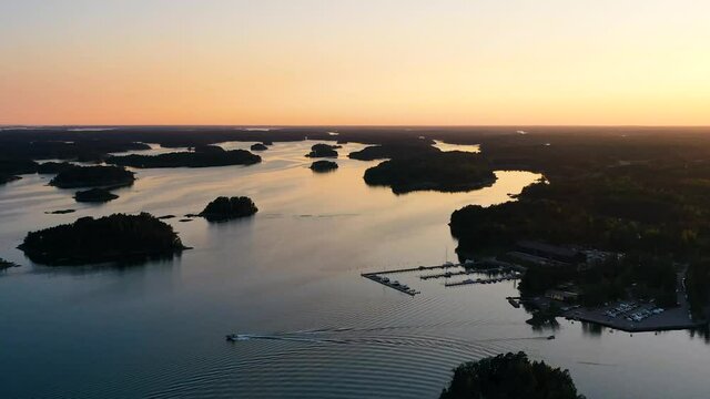 Aerial hyperlapse view of boats leaving and arriving to a harbor, warm, summer sunset, in the Swedish Archipelago, Sweden  - motion time lapse, drone shot
