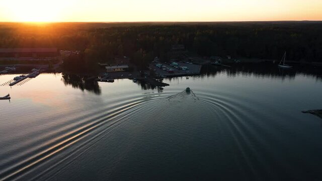Aerial view following a boat arriving at a harbor, sunny evening sunset, in the Stockholm archipelago, in Sweden- tracking, drone shot