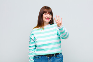 overweight woman smiling and looking friendly, showing number four or fourth with hand forward,...