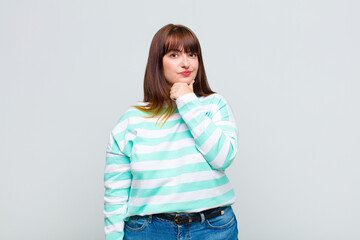 overweight woman looking serious, confused, uncertain and thoughtful, doubting among options or...