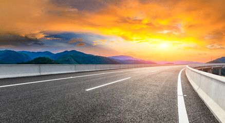Asphalt highway and green mountain natural landscape at sunset.