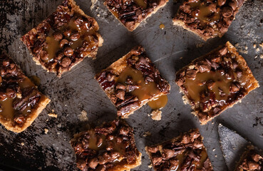 Close up top down view of caramel pecan chocolate chip squares on a sheet pan.