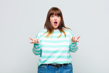 overweight woman feeling extremely shocked and surprised, anxious and panicking, with a stressed...